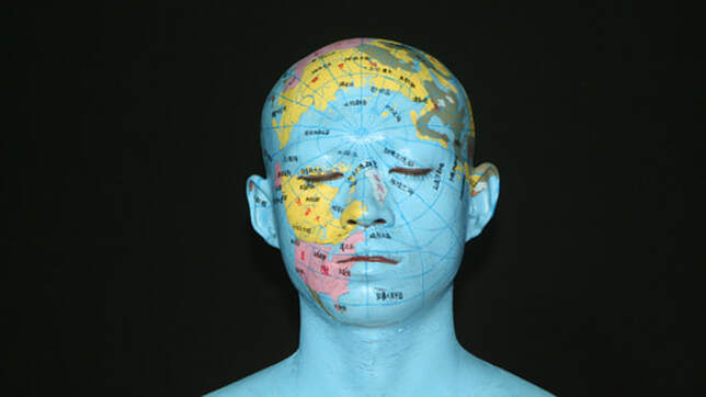 Image: Photograph of a man's face painted with a world map